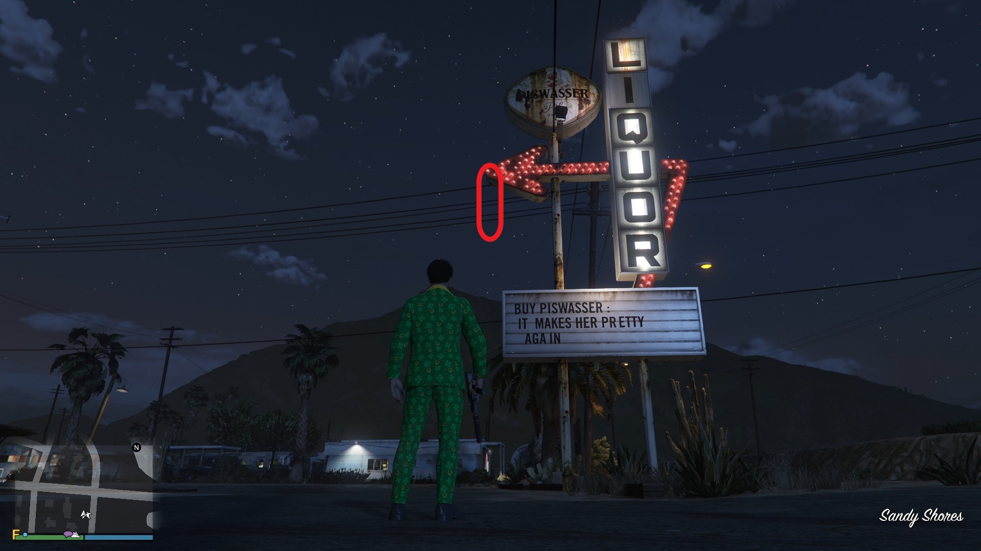 The golden clover will be hanging off the tip of the arrow on the Liquor store sign in Sandy Shores.