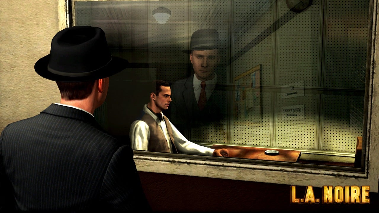Official L.A. Noire screenshot showing Cole Phelps looking at a suspect inside an interrogation room.