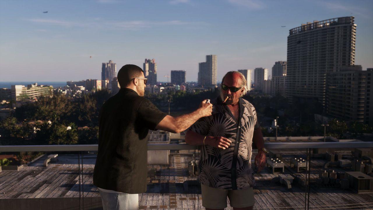 Jason speaks with a man beside the rooftop railing.