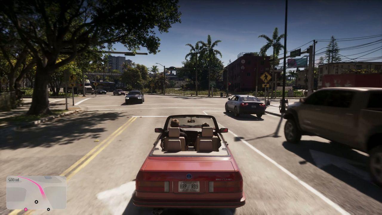 A red convertible joins daytime traffic through the city.