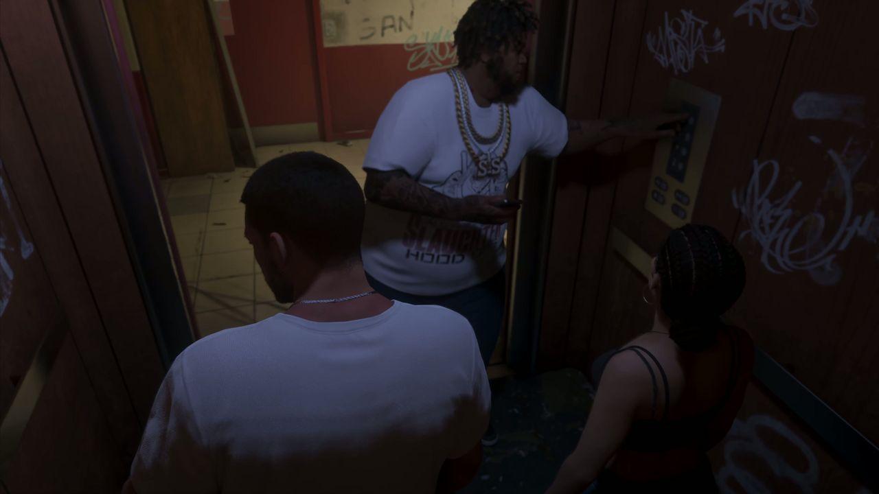 A tattooed member of the group speaks to Jason by the elevator.
