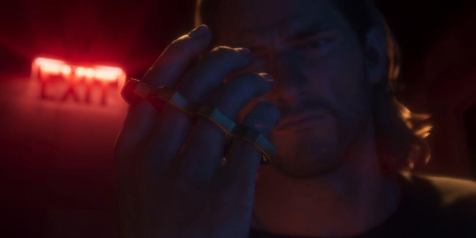 A man holds up rings in a red-lit close-up.